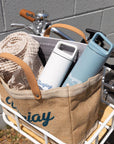 Burlap bag filled with Bluejay e-bike accessories resting in the rack of a Bluejay e-bike.