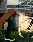 A man holding a guitar case walks toward a Bluejay e-bike in Modern Black.