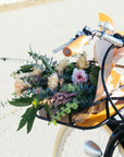 A bouquet of flowers in the front rack of a Bluejay e-bike in Classic Black