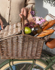 Woman standing with picnic basket filled with food, wine and flowers on top of a Bluejay e-bike