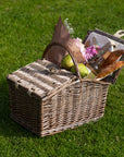 Picnic basket full of food, flowers and a bottle of wine
