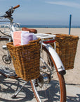 Two pannier Nantucket baskets on a Bluejay e-bike in Modern White at the beach.