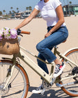 A woman rides a Bluejay Premiere Lite e-bike in Sunkissed Ivory.