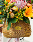 Bouquet of flowers in basket on front of a Bluejay e-bike in Blush Pink. 