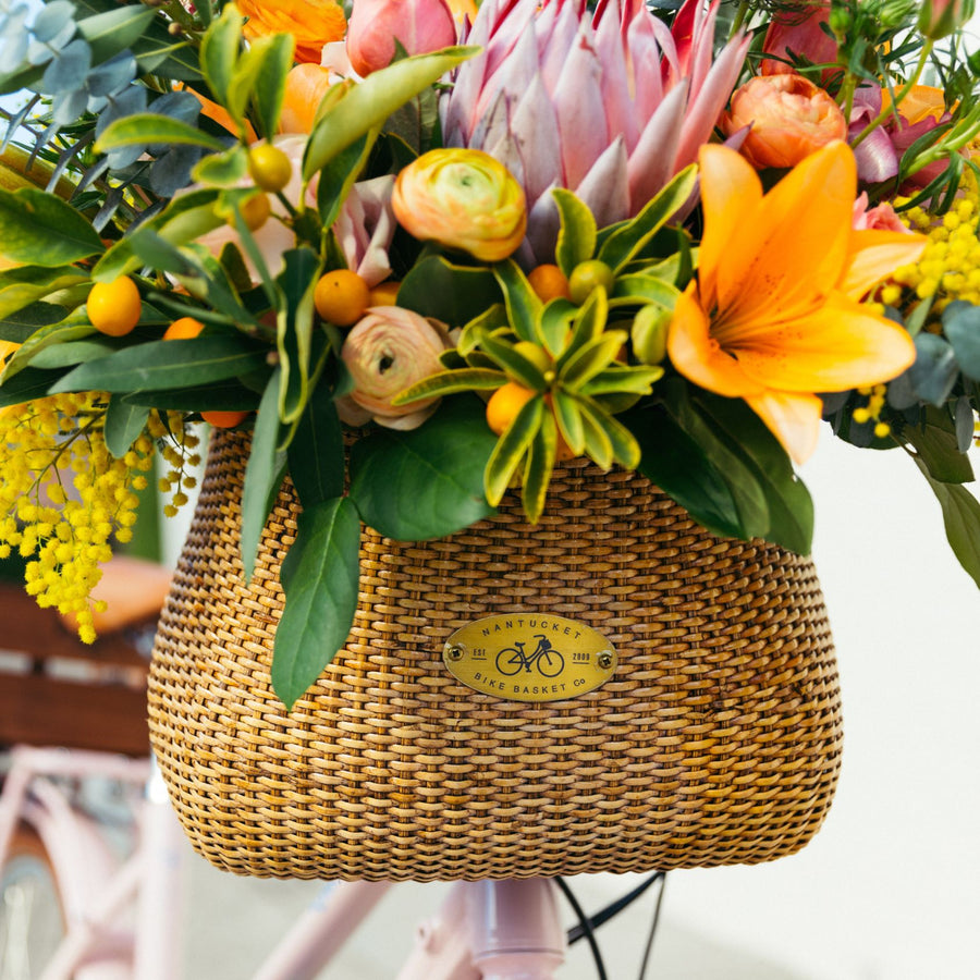 Bouquet of flowers in basket on front of a Bluejay e-bike in Blush Pink. 