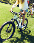 A girl riding a Bluejay WILD Kids' e-bike in Mint Green.