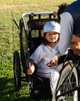 A mother straps her child into a Burley bike trailer behind a Bluejay e-bike. 