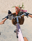 Bluejay e-bike in Blush Pink wth front basket of flowers in cup holder 