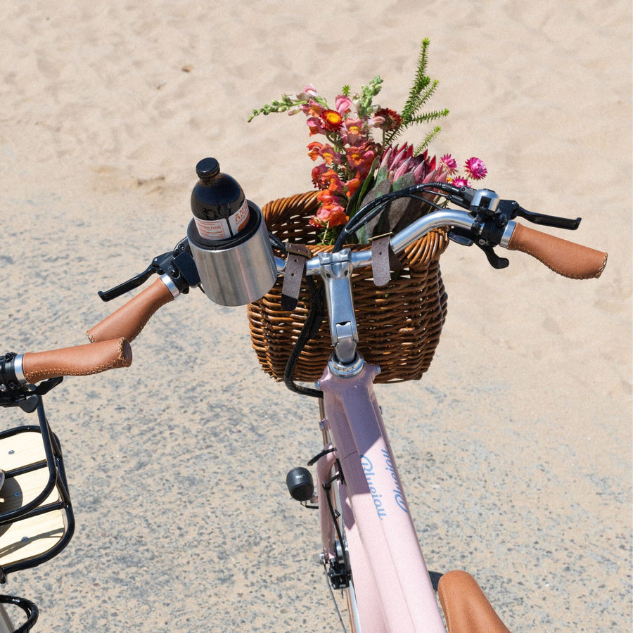 Bluejay e-bike in Blush Pink wth front basket of flowers in cup holder 