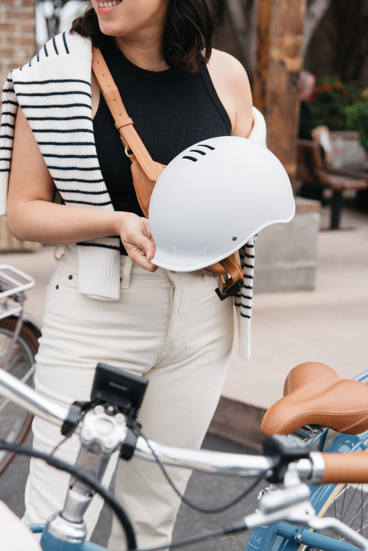 Woman holding white Thousand helmet with Bluejay Premiere Edition e-bike