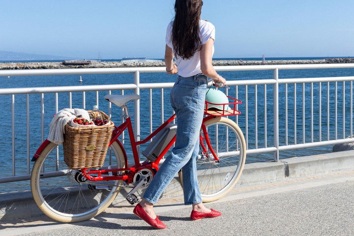 Woman walking a Bluejay Premiere Edition e-bike in Cherry Red