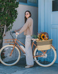 Woman standing with Bluejay Premiere Edition e-bike in Luxe Camel 