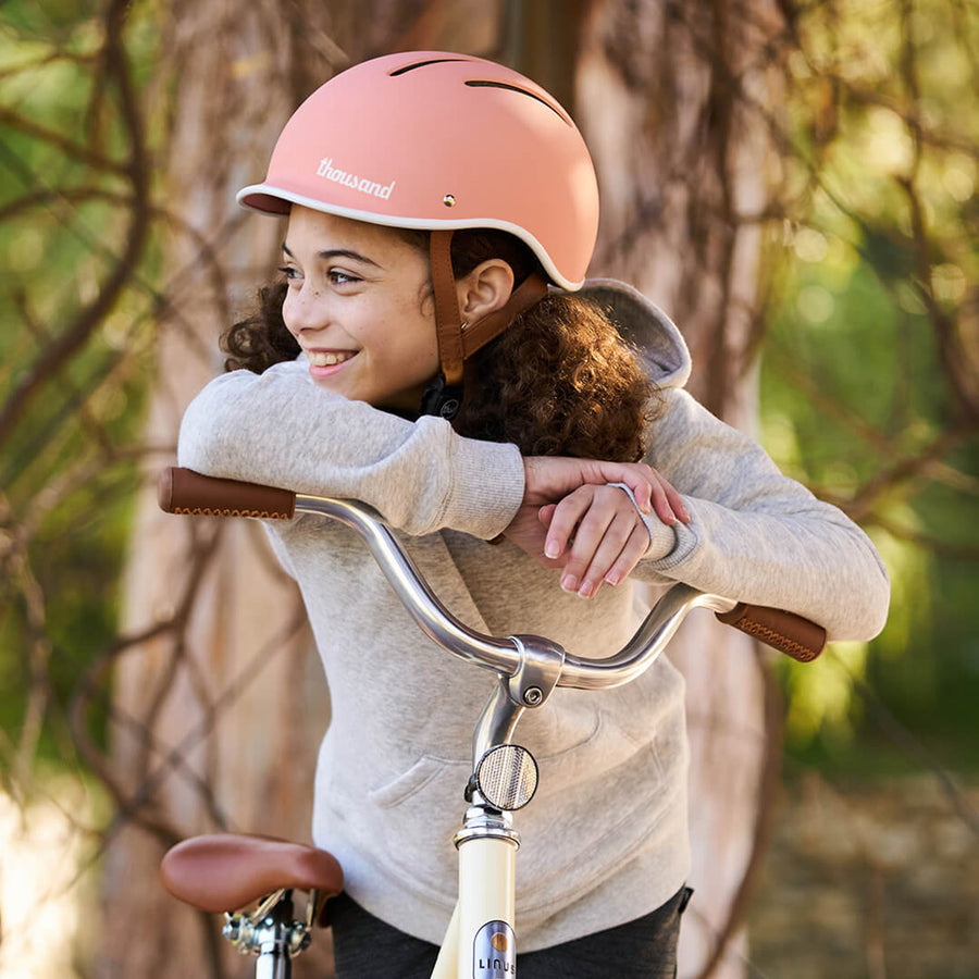 Kid wearing Thousand Jr. bike helmet in Pink